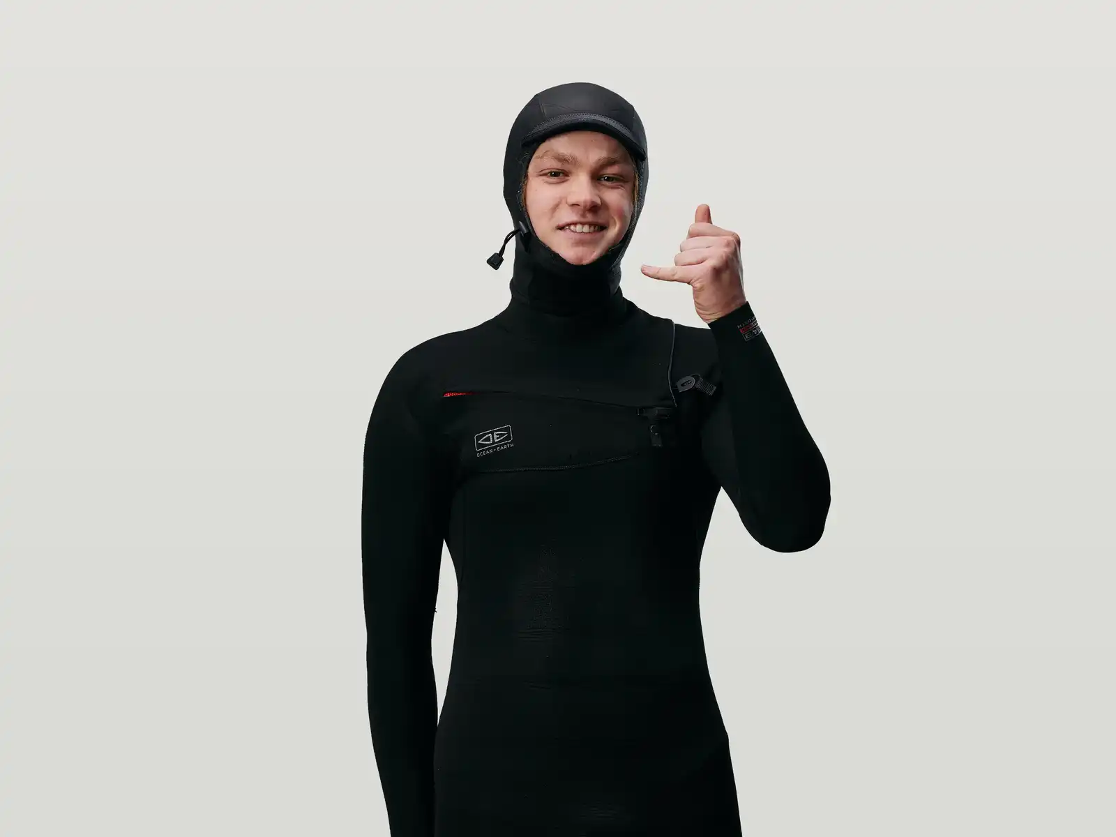 Awa in a wetsuit smiling doing a shaka hand sign