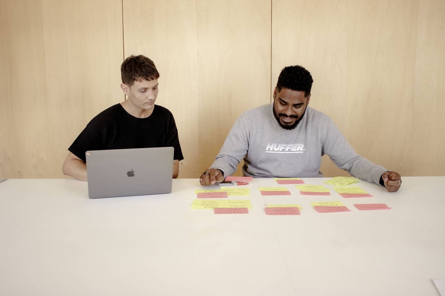 Two men sitting at a table sorting post it notes